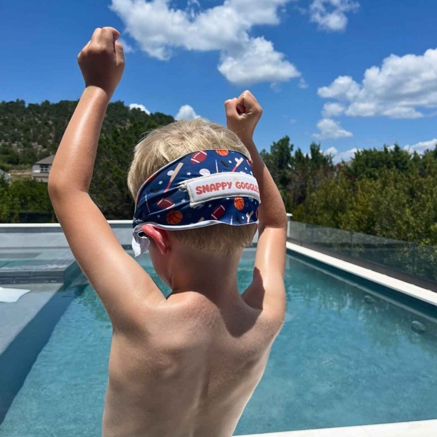 Child wearing a sports theme fabric swim goggles with 'Snappy Goggles' at a poolside on a sunny day.