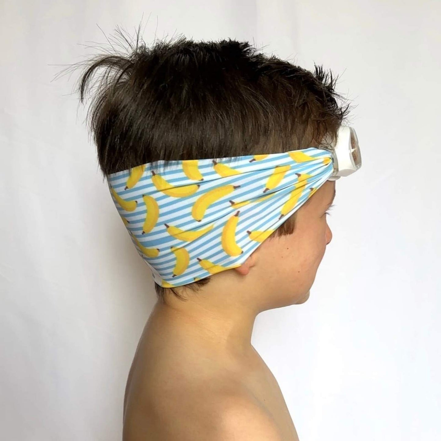 side view of a boy wearing blue and white stripes with yellow bananas kid swim goggles with adjustable fabric strap and floatable goggles – Snappy Goggles