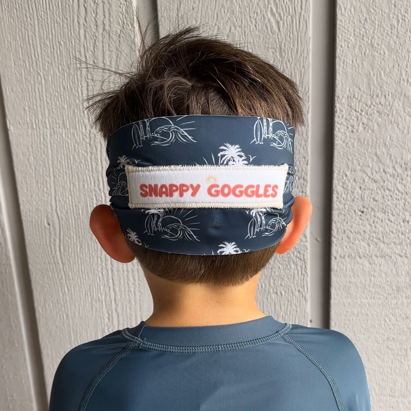 Child wearing a navy beach inspired fabric strap swim goggles - Snappy Goggles