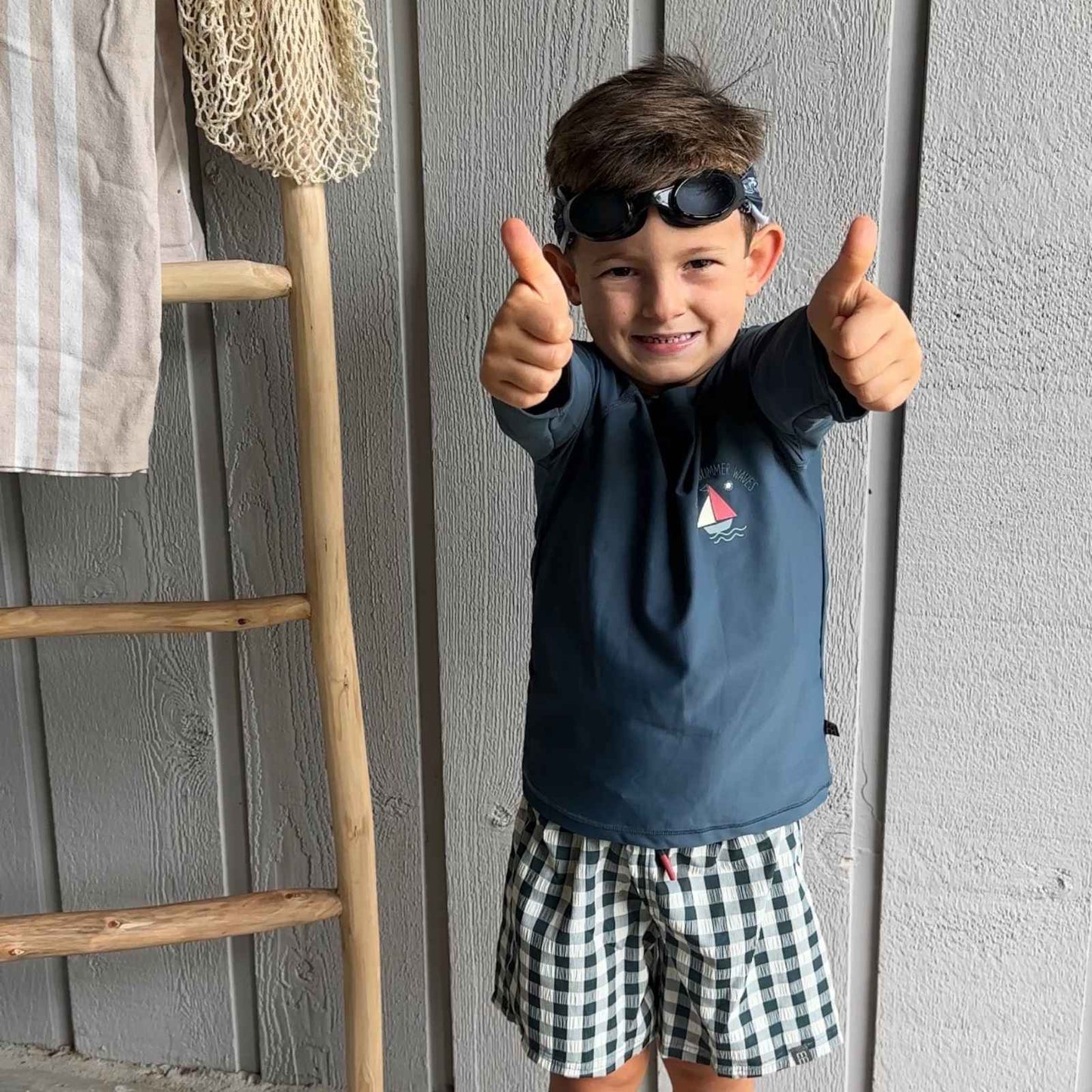 Child giving thumbs up wearing beach vibes fabric swim goggles on top of his head - Snappy Goggles