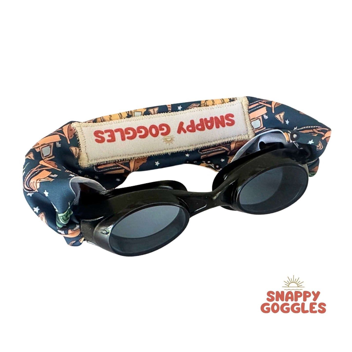 Black swim goggles with a construction patterned fabric strap labeled 'Snappy Goggles' floatable swim goggles for kids.
