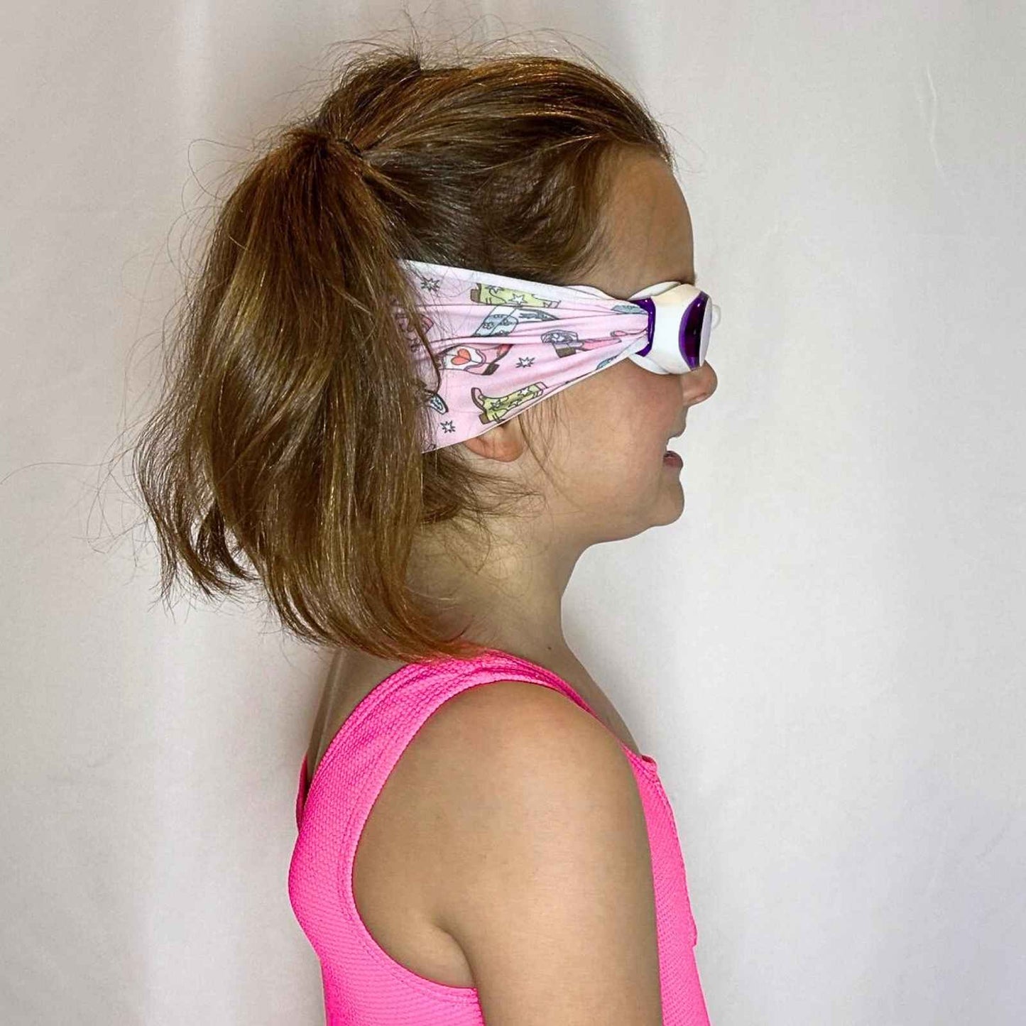 side view of colorful pink purple green cowgirl boot kids swim goggles with adjustable fabric strap and floatable goggles – Snappy Goggles