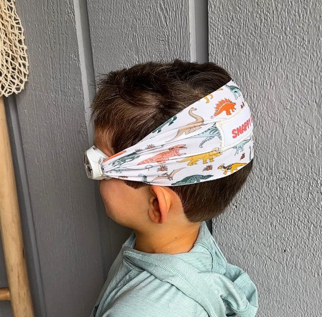 Child wearing a dinosaur-patterned fabric strap swim goggles - Snappy Goggles