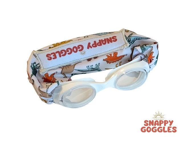 Snappy Goggles with dinosaur patterned fabric strap on a white goggle frame