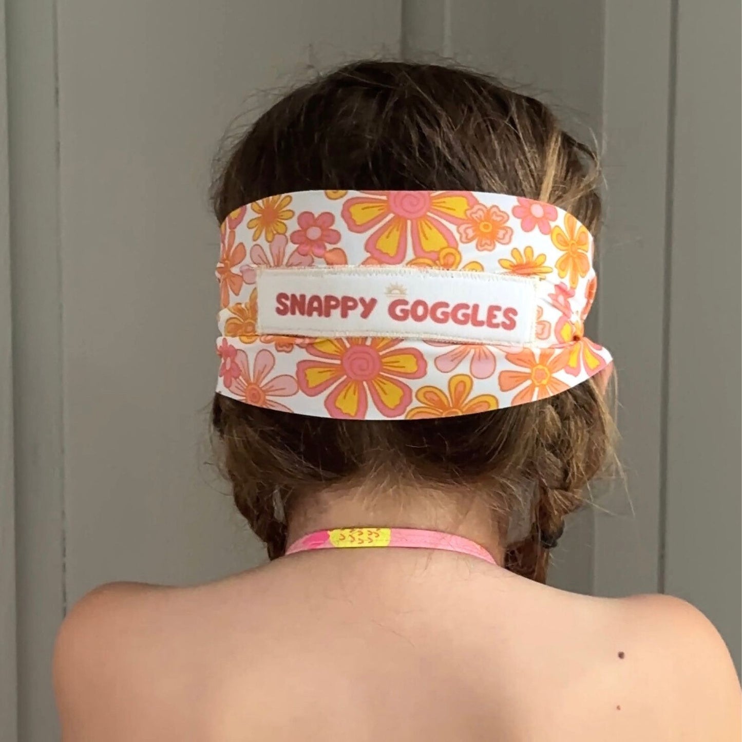 back view of pink yellow and orange floral kid swim goggles with adjustable, fabric strap – Snappy Goggles