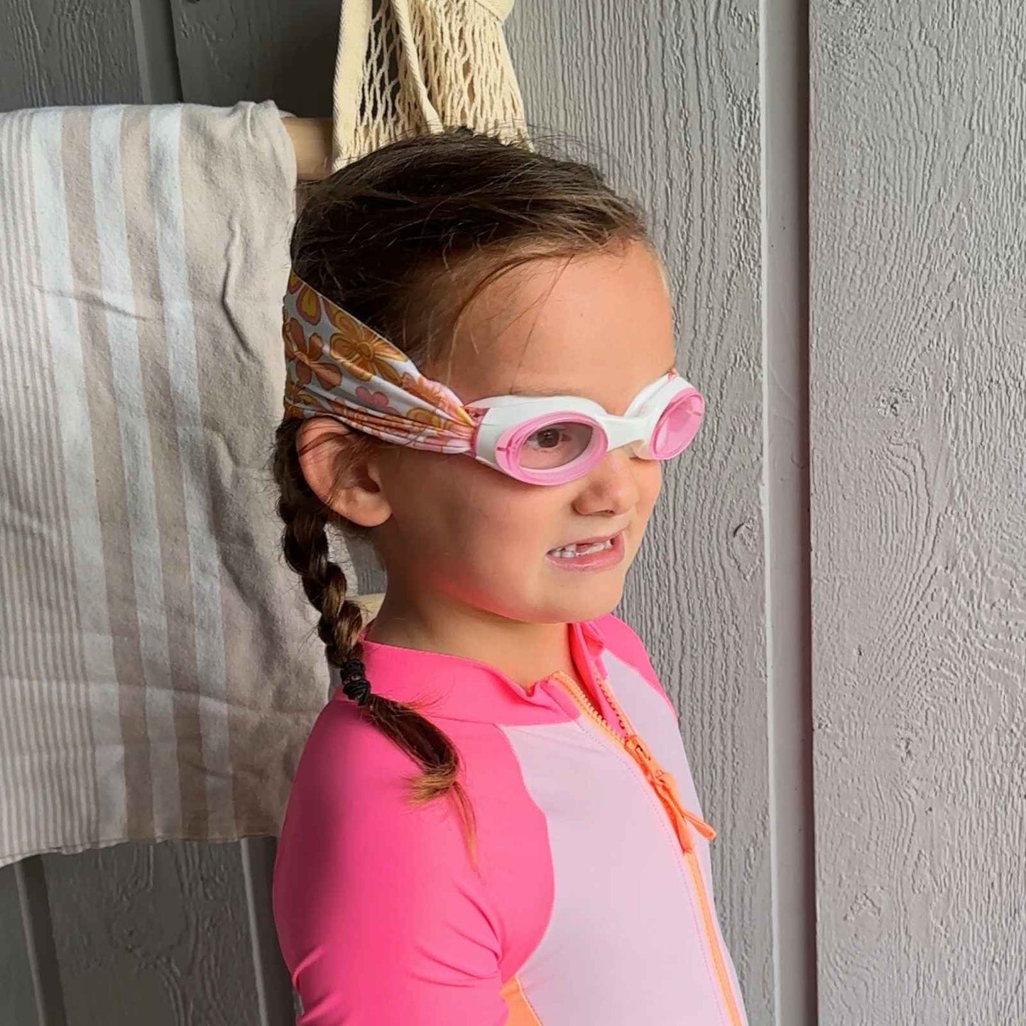 Young girl wearing pink and orange floral fabric swim goggles that don't pull hair - Snappy Goggles