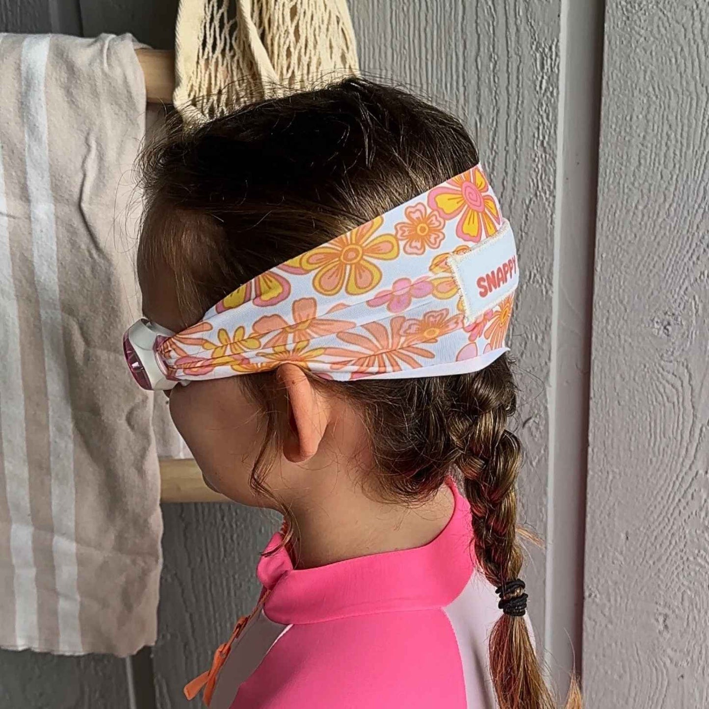 side view of orange yellow and pink flower kids swim goggles with adjustable fabric strap and floatable goggles – Snappy Goggles