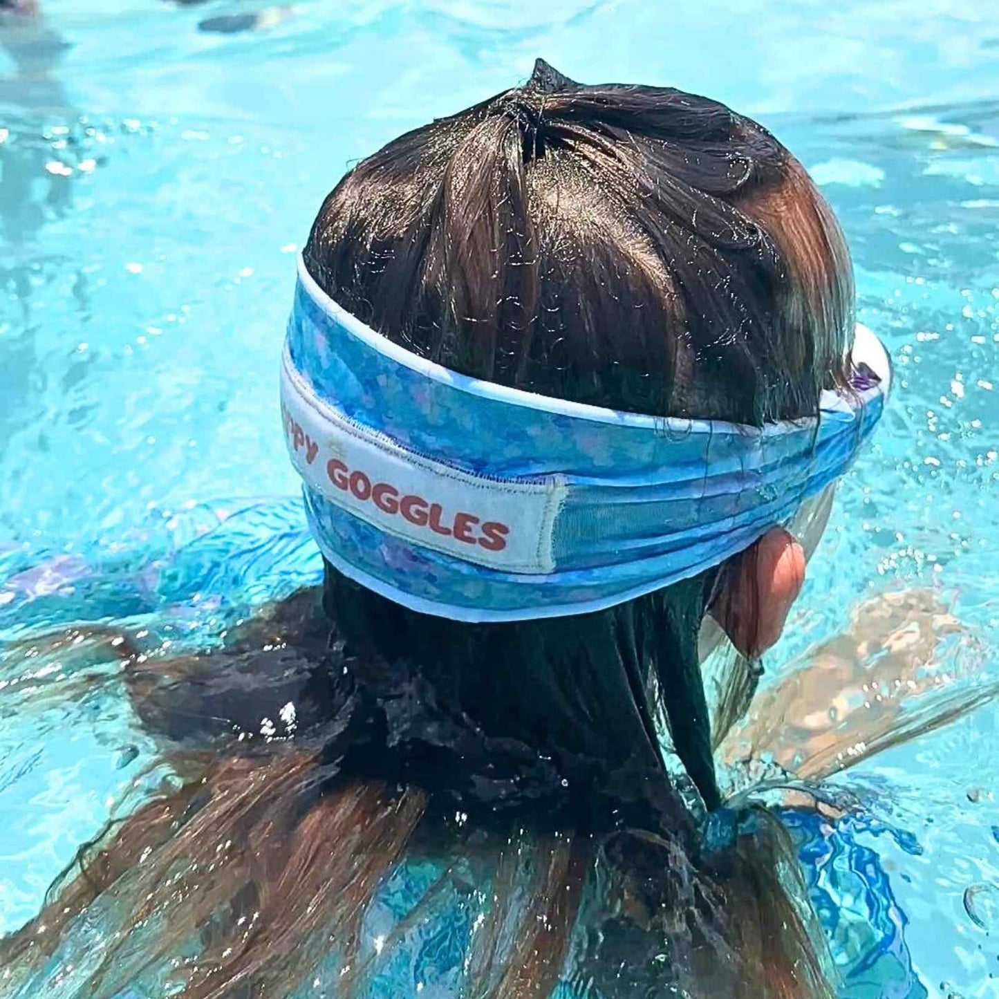 Girl wearing a mermaid pattern fabric strap swim goggles that don't pull hair - Snappy Goggles