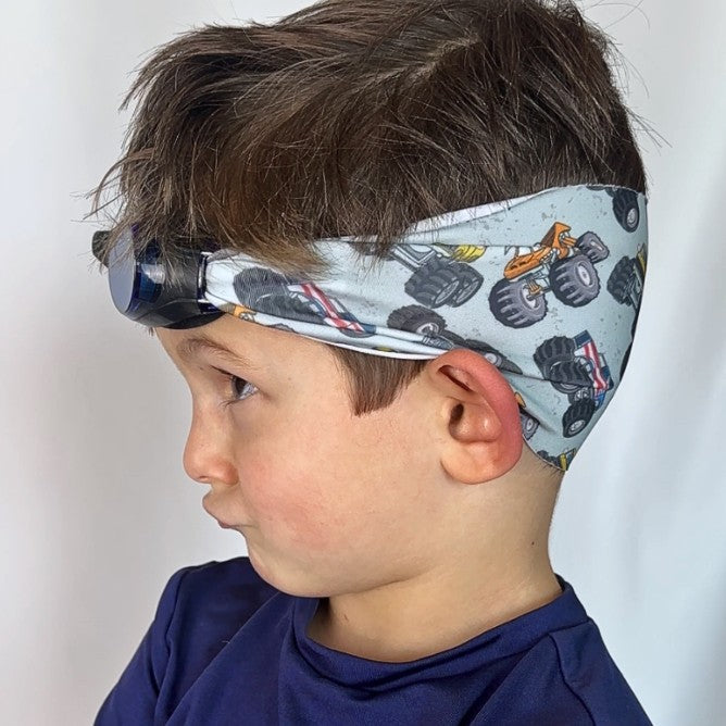 Child wearing a adjustable fabric swim goggles with monster truck pattern, goggles don't pull hair. - Snappy Goggles