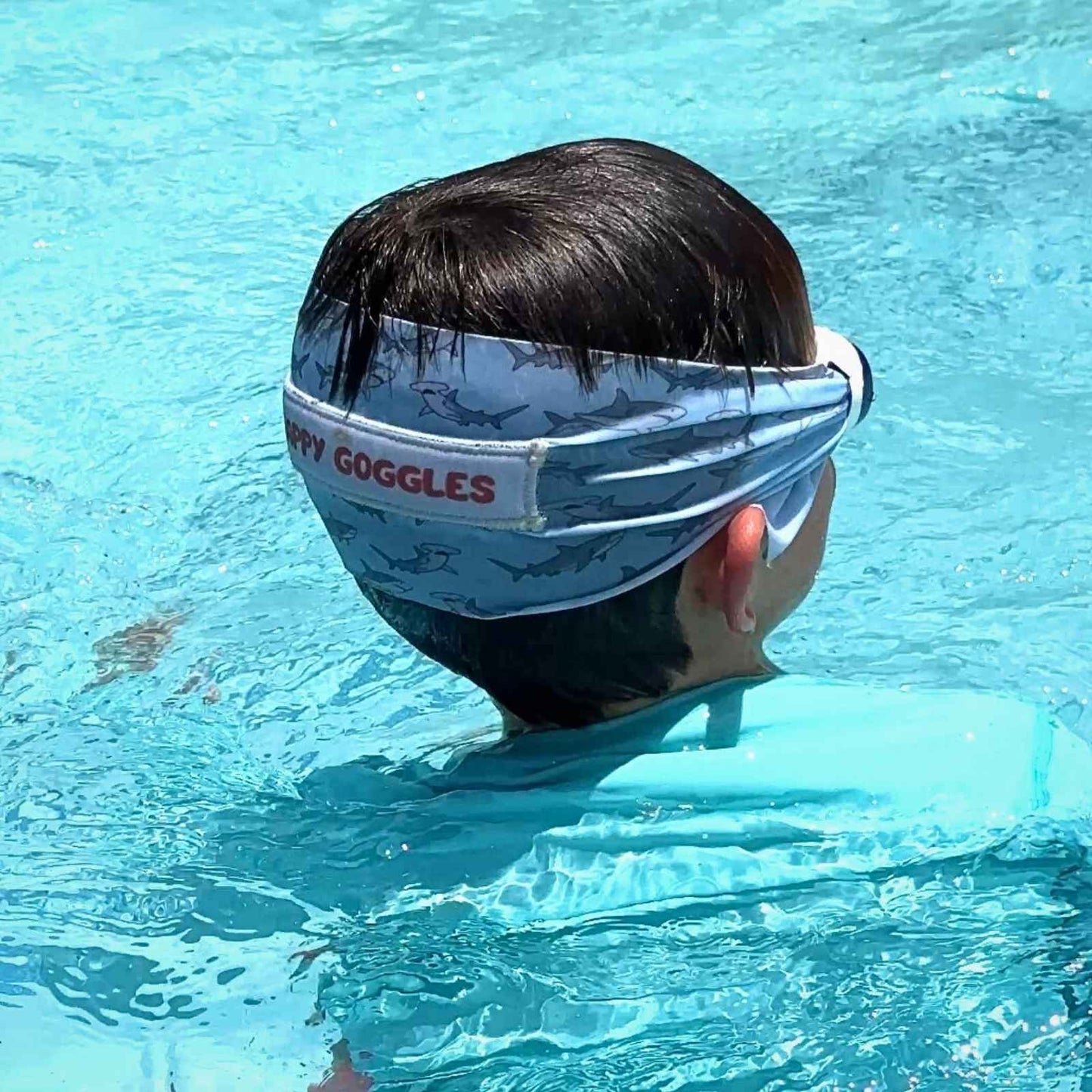 Boy swimming with blue shark fabric strap swim goggles that don't pull hair - Snappy Goggles