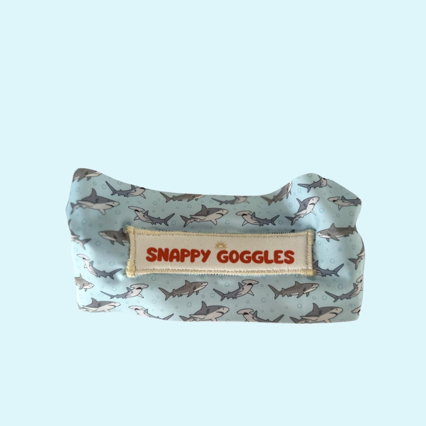 Shark-patterned fabric strap swim goggles with 'Snappy Goggles' label