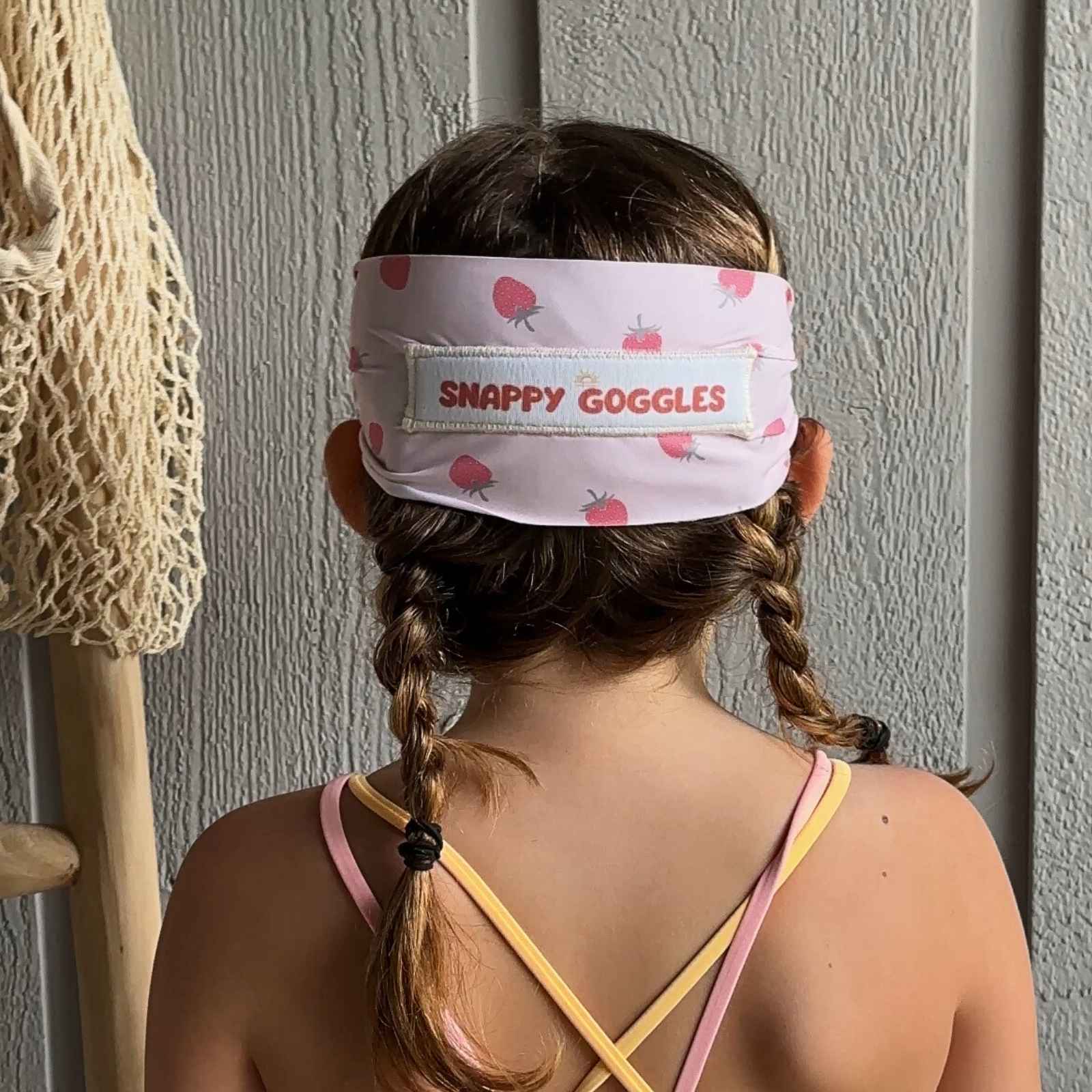 back view of pink strawberry pattern kids swim goggles with adjustable, fabric strap – Snappy Goggles