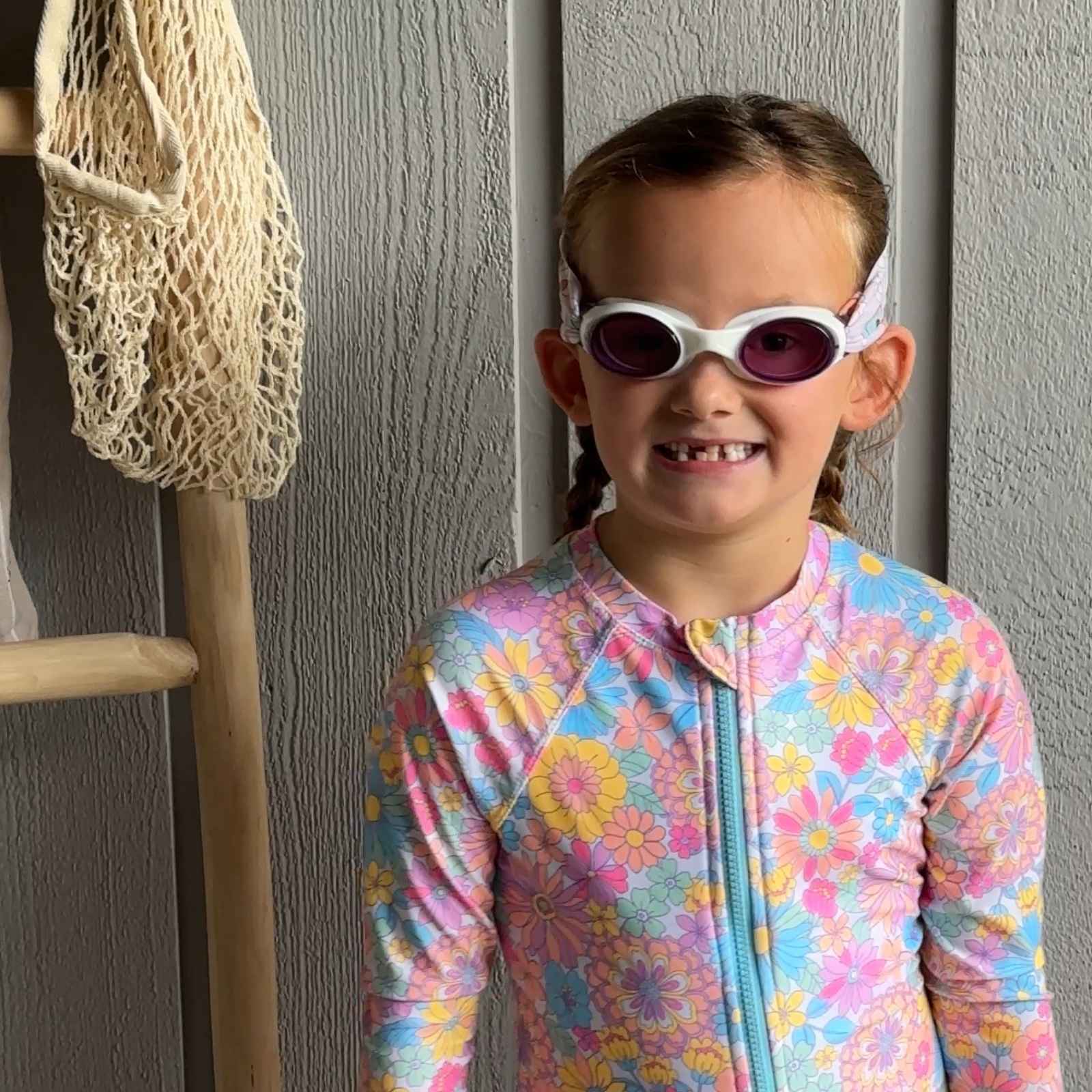 Child in a colorful swimsuit wearing colorful smiley face fabric swim goggles- Snappy Goggles