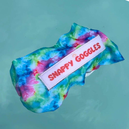 Colorful tie-dye fabric swim goggles floating on top of water - Snappy Goggles
