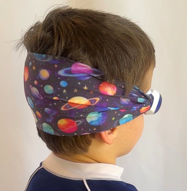 Child wearing a colorful space-themed fabric swim goggles with planets and stars - Snappy Goggles