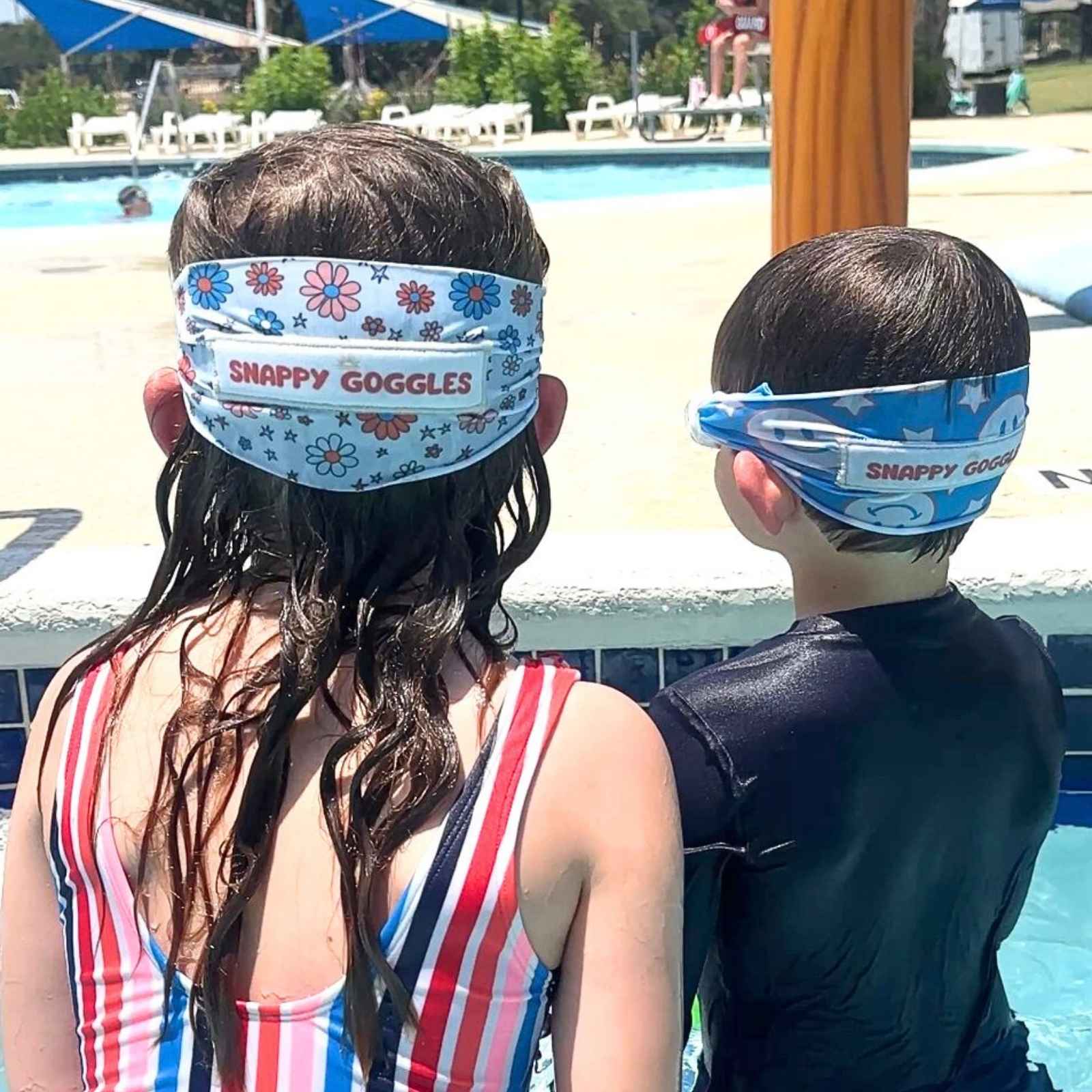 Two children wearing 'Snappy Goggles' fabaric strap swim goggles by a pool. 