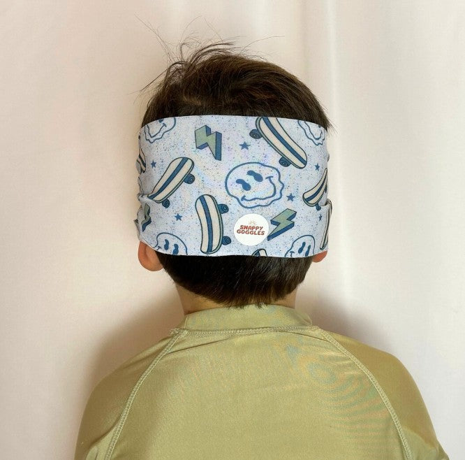kid back view of blue swim goggles skateboards and smiley faces, with soft fabric adjustable strap, floatable swim goggles – Snappy Goggles